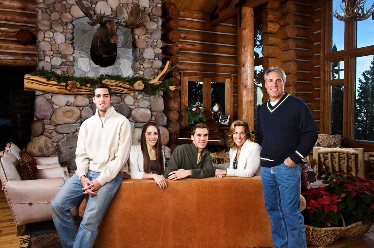 Family portrait created inside a mountain home with a stone fireplace